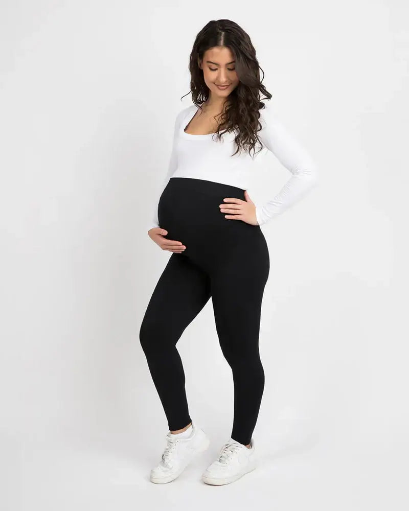 Femme enceinte portant un legging de grossesse taille haute, alliant confort et élégance.